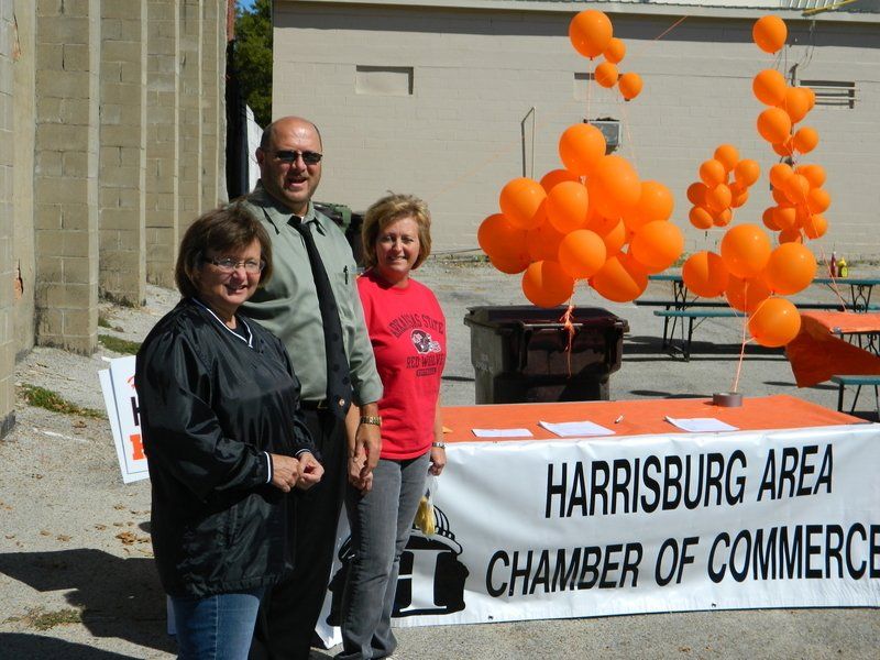 Three people standing in front of a harrisburg area chamber of commerce table