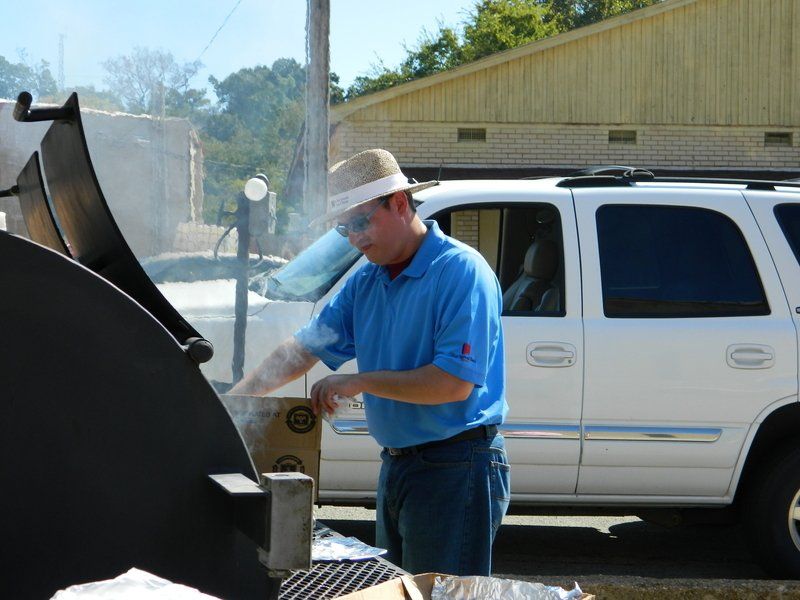 A man in a blue shirt is standing in front of a white suv