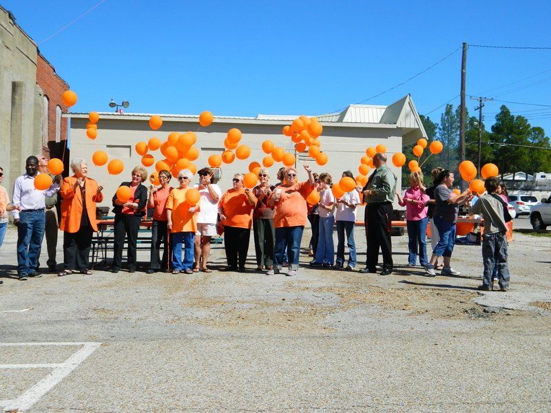 A group of people holding orange balloons in a parking lot