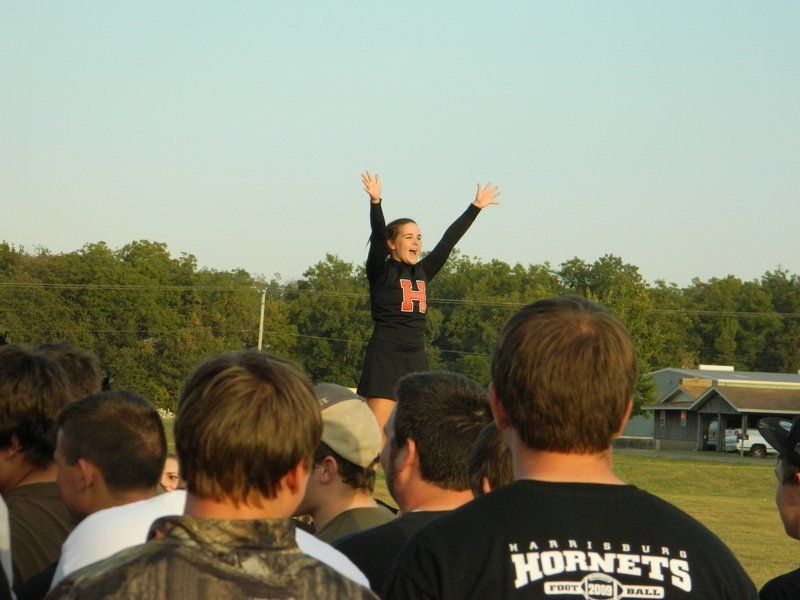 A cheerleader wearing a hornets shirt stands in front of a crowd