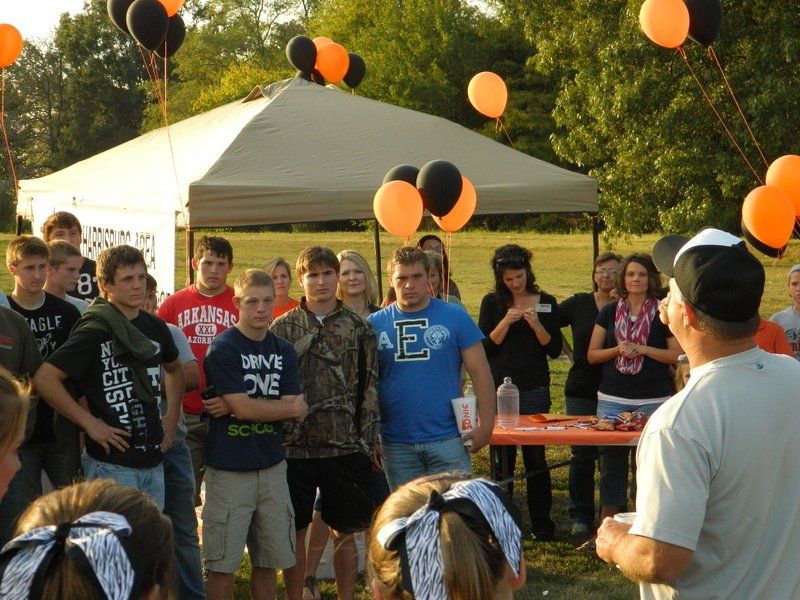 A man in a blue shirt with the letter f on it stands in front of a group of people