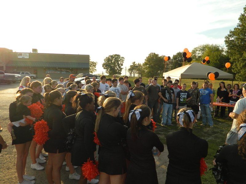 A group of cheerleaders are gathered in a parking lot
