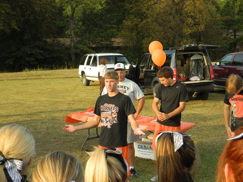 A group of people standing in a field with a gildan box in the foreground