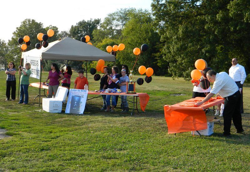 A group of people standing around a table with balloons in the background
