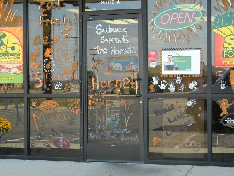 A store front with a sign that says subway supports the hornet