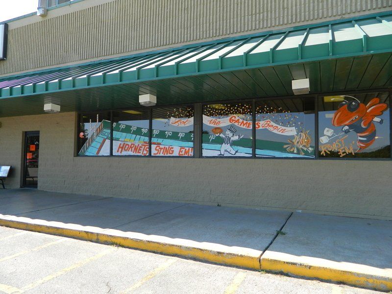 A building with a green awning has a painting of a hockey player on the windows