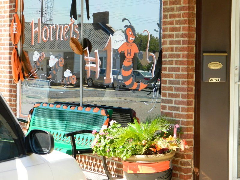 A white car is parked in front of a store called hornets