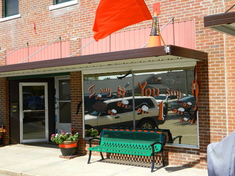 A green bench sits in front of a store that says you say