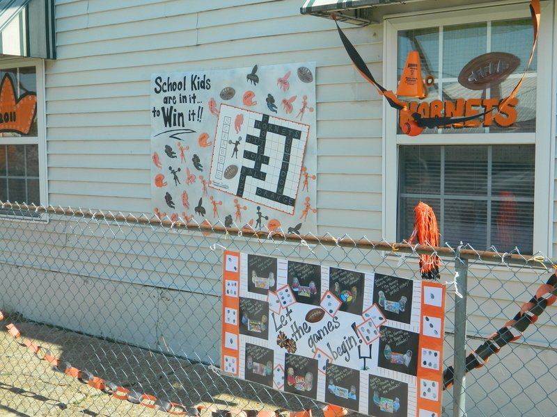 A sign on a chain link fence says school kids win