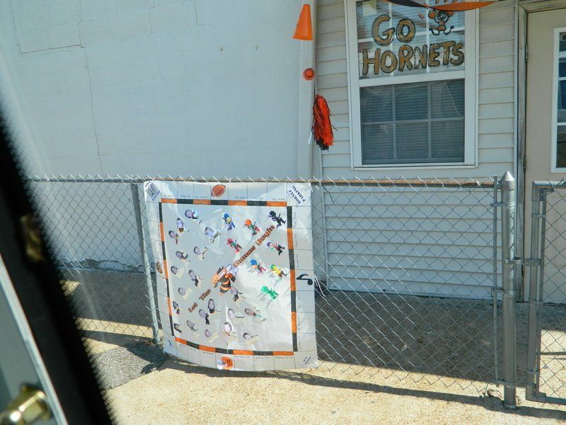 A sign on a chain link fence says go hornets