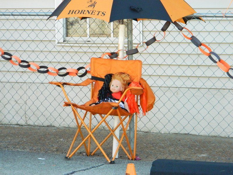 A child sits in an orange chair under an umbrella that says hornets