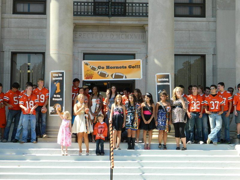 A group of people standing in front of a building with a sign that says go hornets go