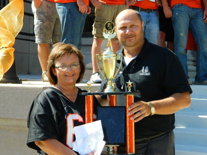 A man and woman holding a trophy with the number 6 on it