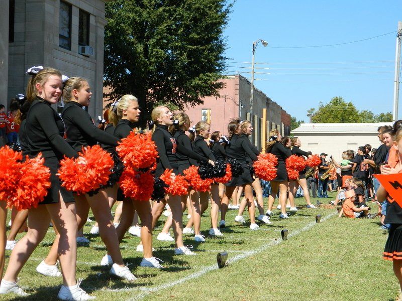 A group of cheerleaders with orange pom poms on a field