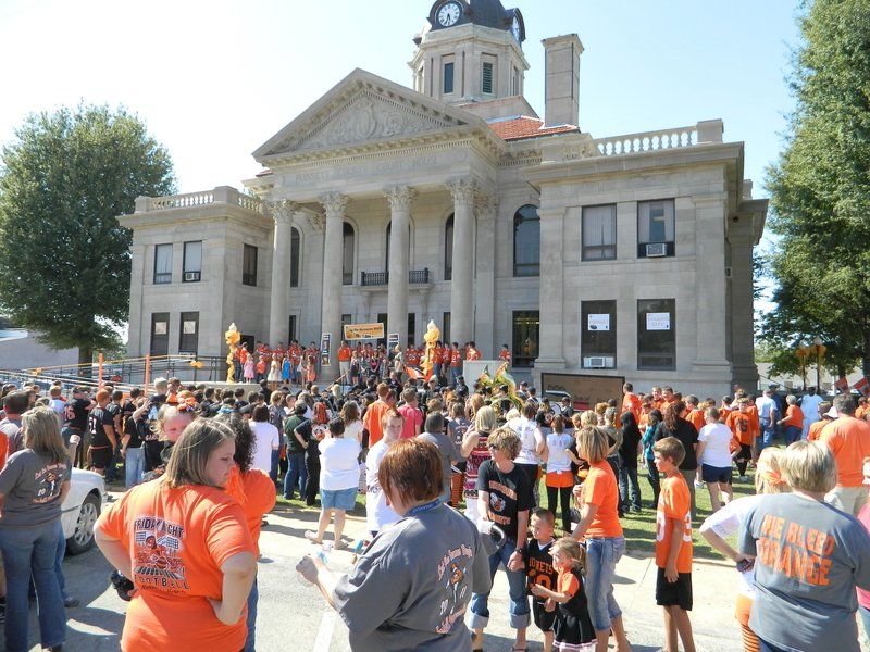 A crowd of people are gathered in front of a large building