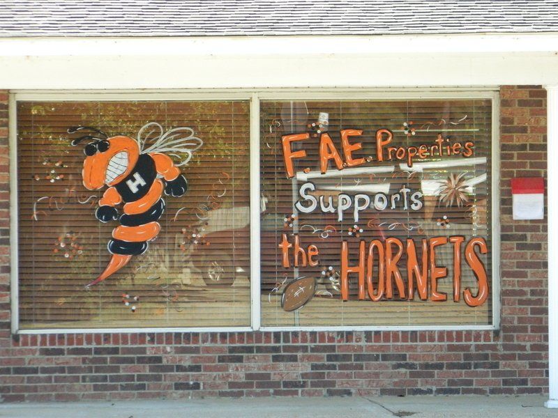 A brick building with a window that says fae properties supports the hornets