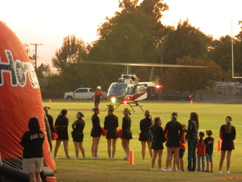 A group of cheerleaders standing in front of a helicopter that says hooters