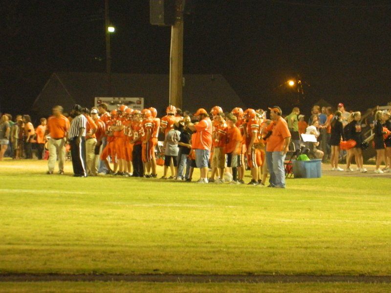A group of people are standing on a field at night