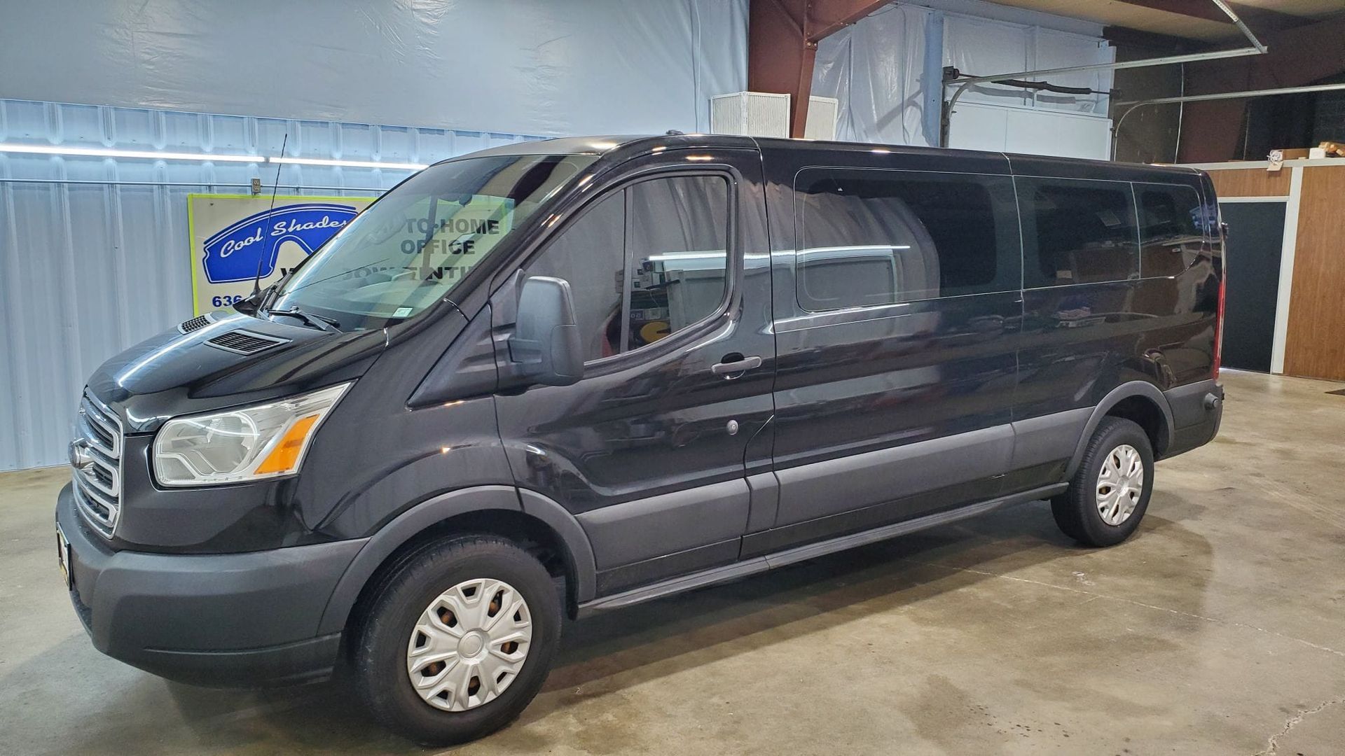 Dark gray passenger van parked indoors on a concrete floor.