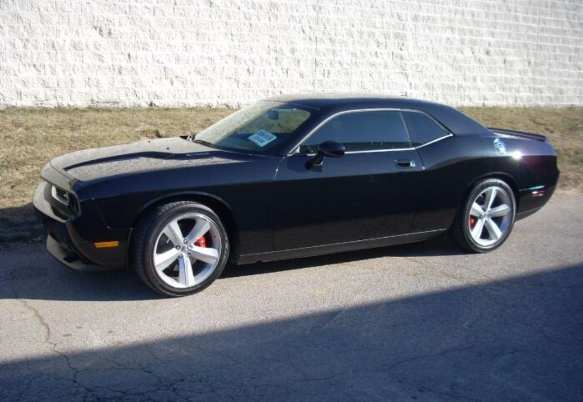 Black sports coupe parked beside a wall on a sunny street