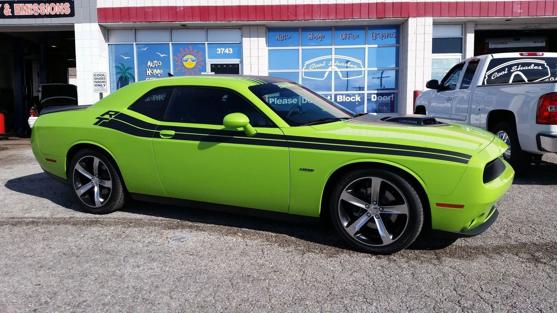 Bright lime green sports car parked outside a storefront with blue windows