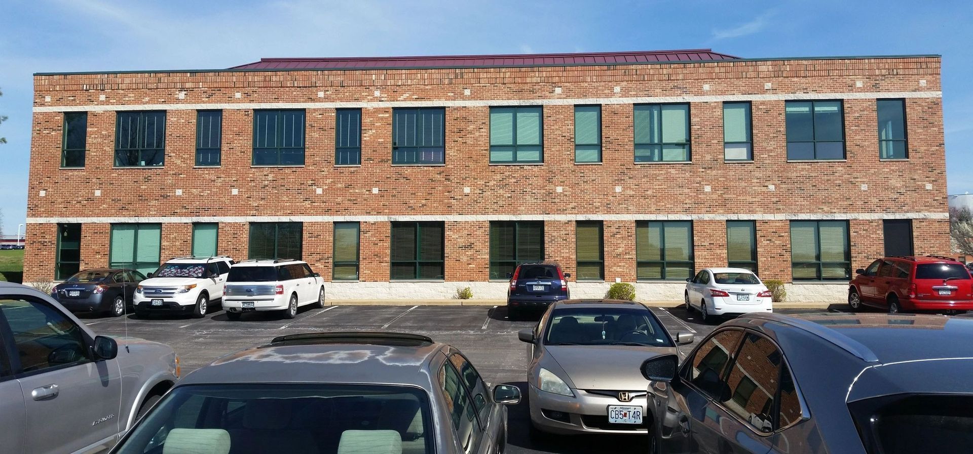 Brick industrial building with many windows and parked cars in front