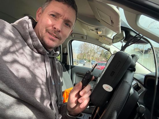 Auto locksmith Gerry programming a vehicle key on-site using specialist key coding equipment.