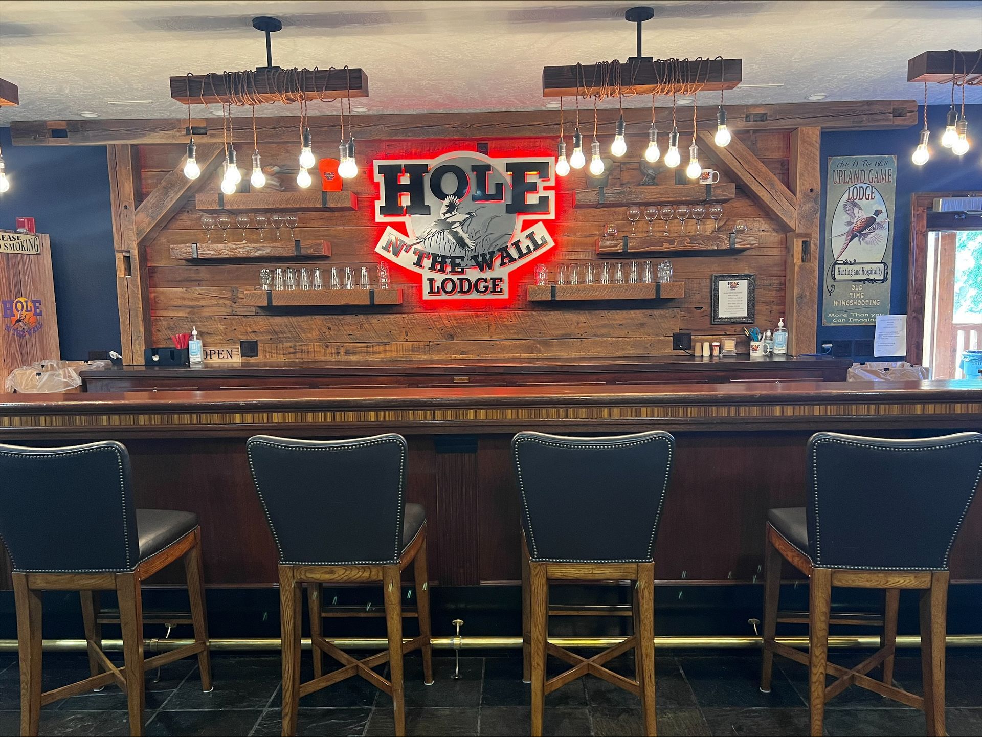 A bar with a sign on the wall that says hole in the wall lodge.