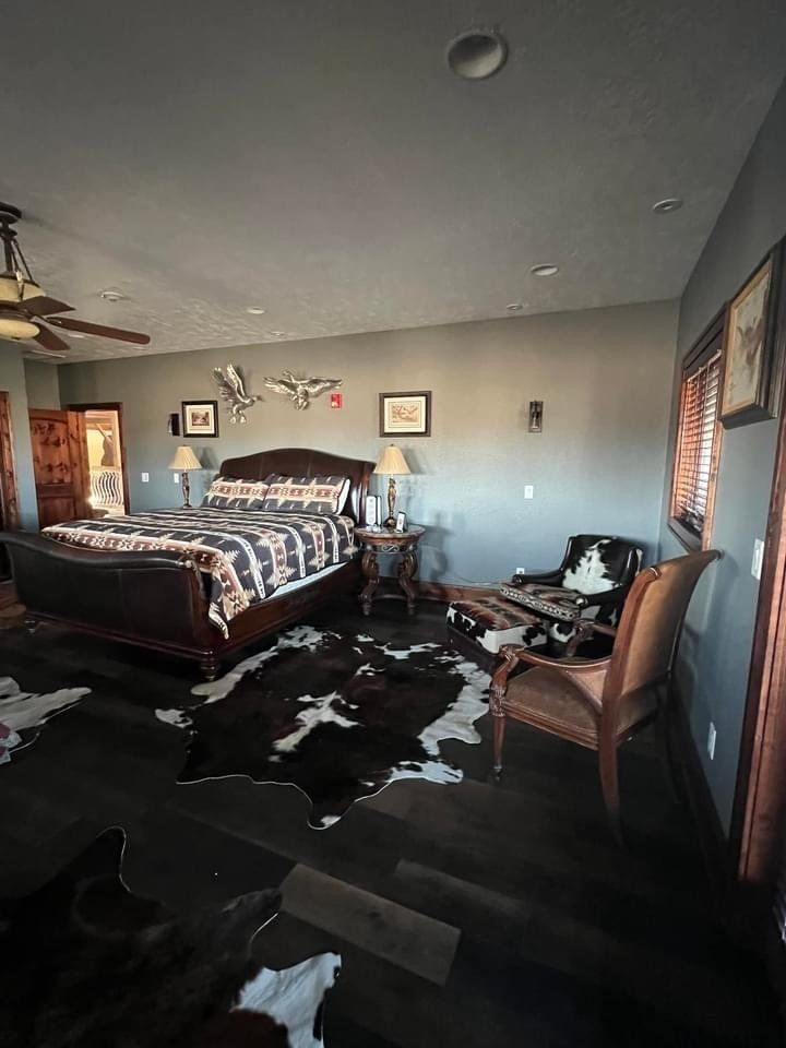 A bedroom with a large bed , chairs , and a cowhide rug.
