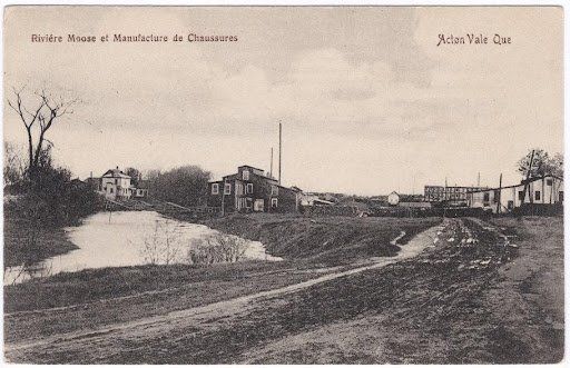 Une photo en noir et blanc d'une rivière avec une maison en arrière-plan.