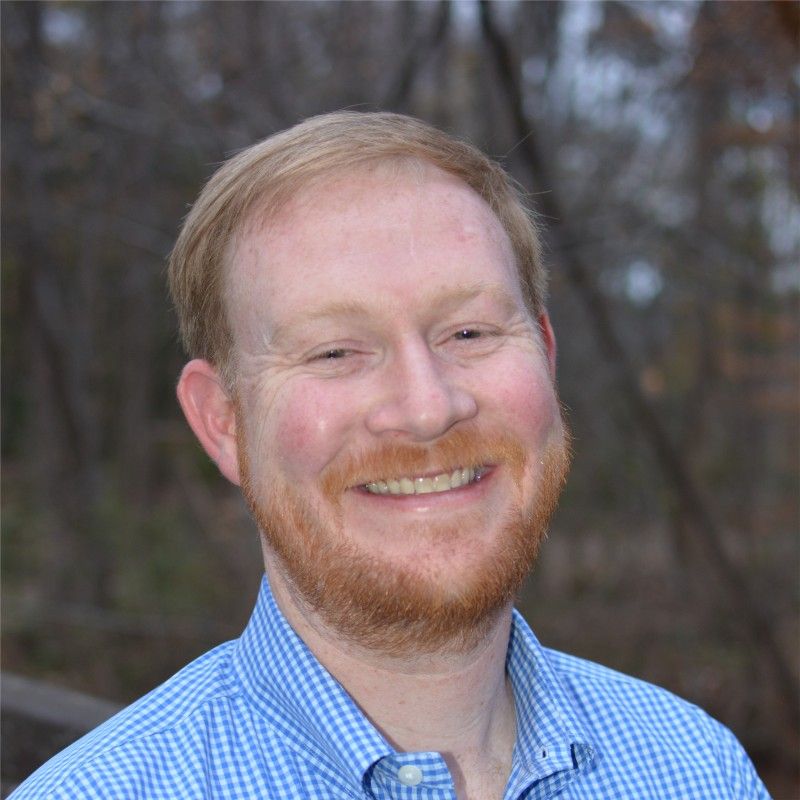 A man with a beard and a blue shirt is smiling for the camera.