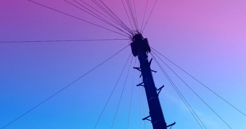 Ground up view of a telephone post with cables in all directions