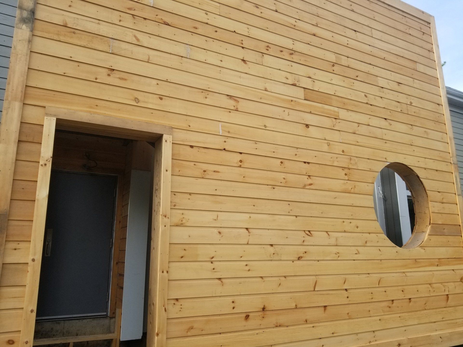 Façade de bâtiment lambrissée avec une porte et une découpe pour une fenêtre ronde