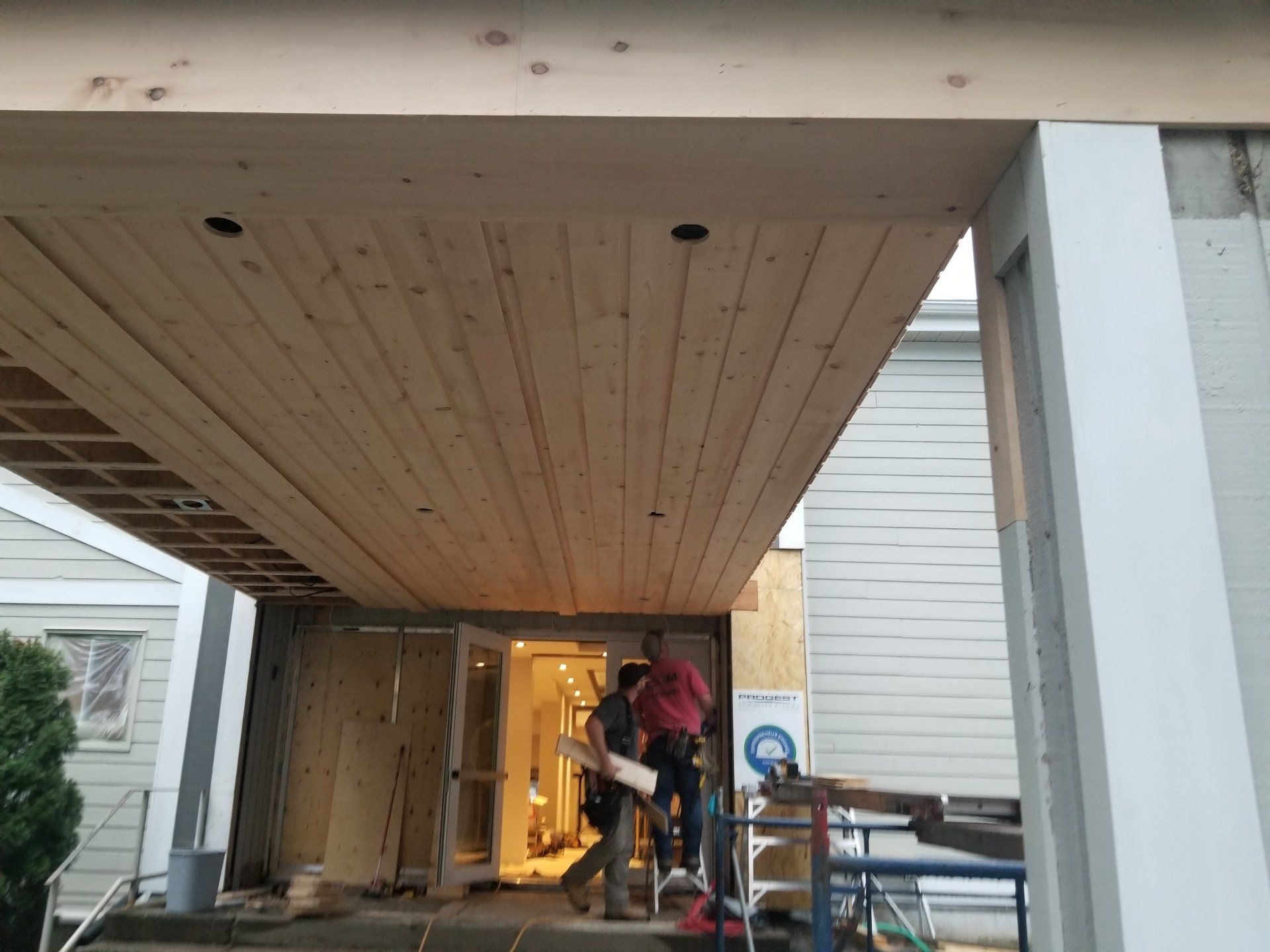 Deux ouvriers installent un plafond sous une entrée d'allée couverte