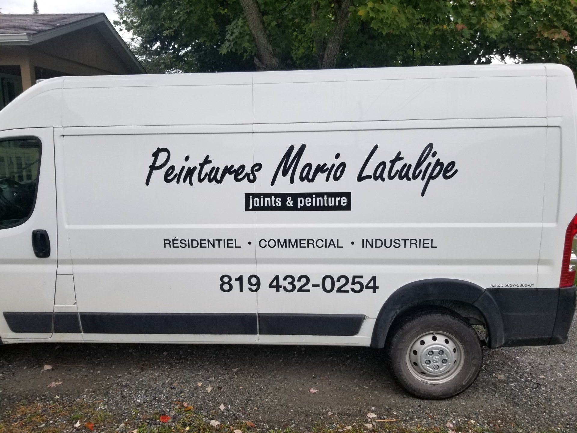 Camionnette blanche avec l'inscription « Peintures Mario Latalipe » et un numéro de téléphone, garée à l'extérieur.