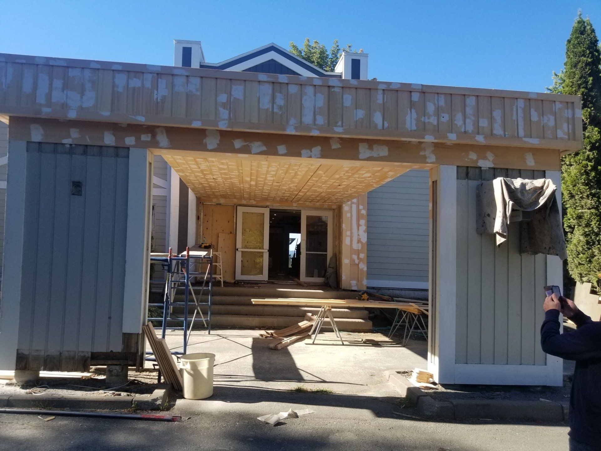 Maison partiellement démolie, charpente apparente, débris et ouvriers en pleine rénovation