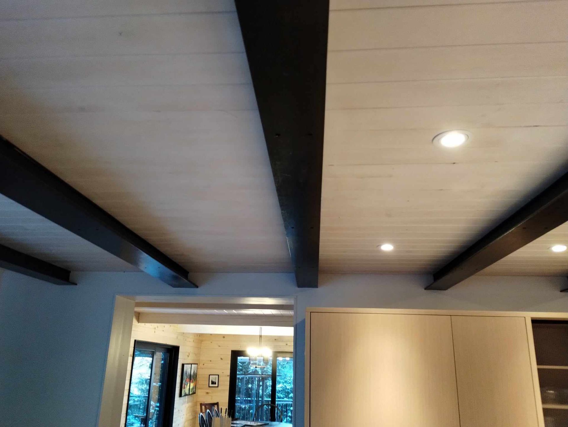 Plafond avec poutres en bois sombre et spots encastrés au-dessus de l'intérieur d'une pièce