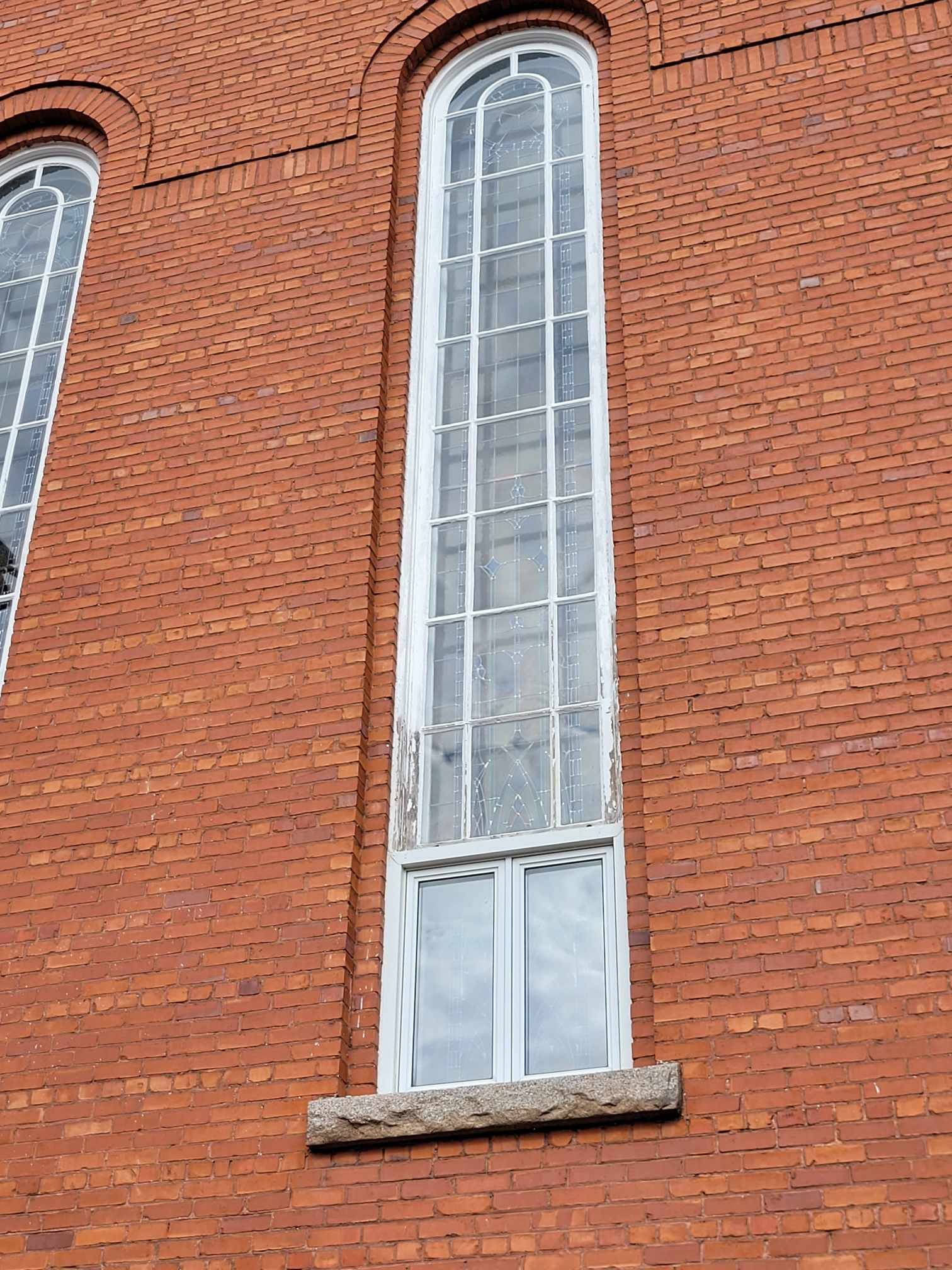 Haute fenêtre cintrée étroite sur la façade d'un bâtiment en briques rouges