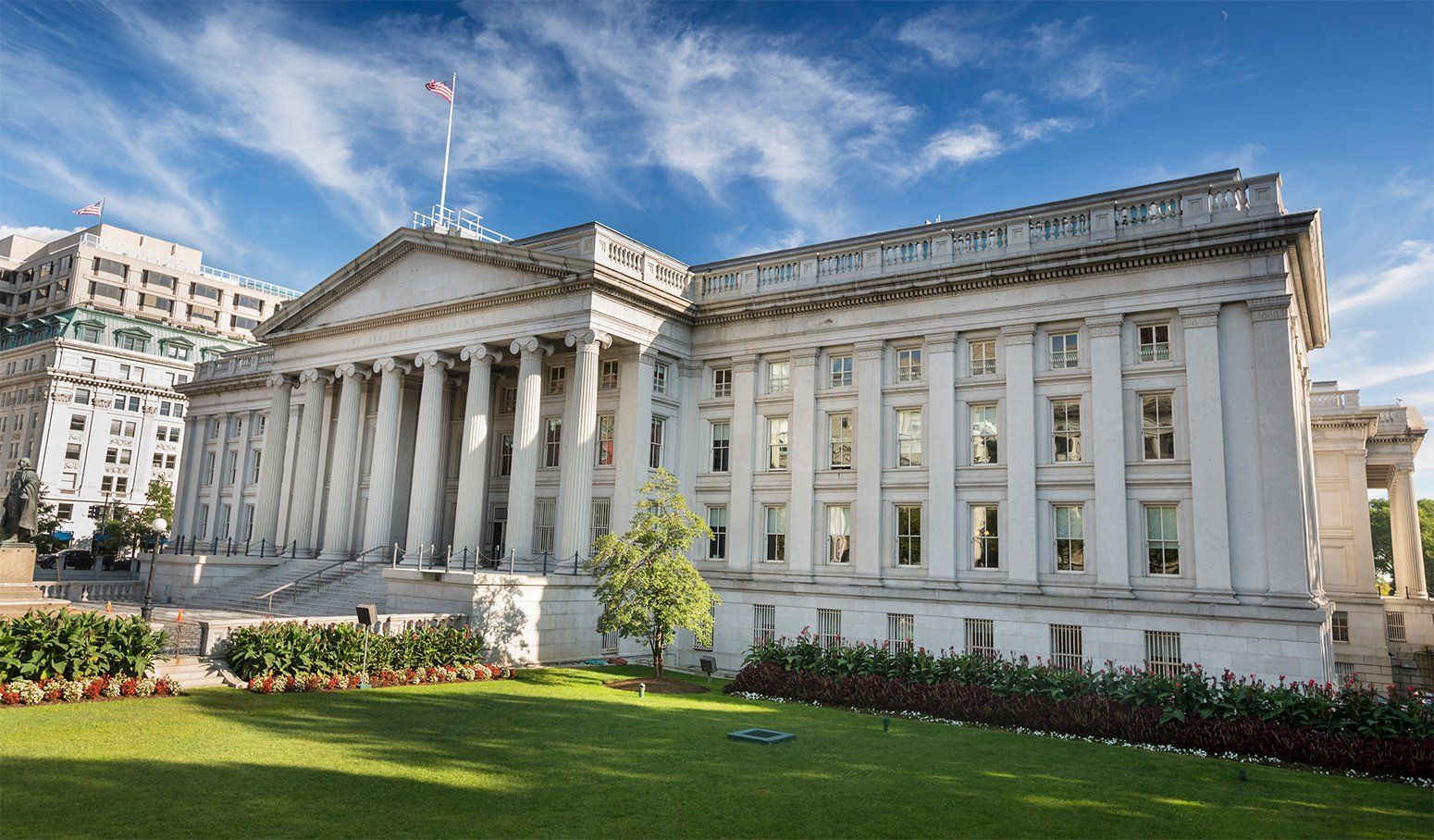 A large white building with columns and a flag on top of it.