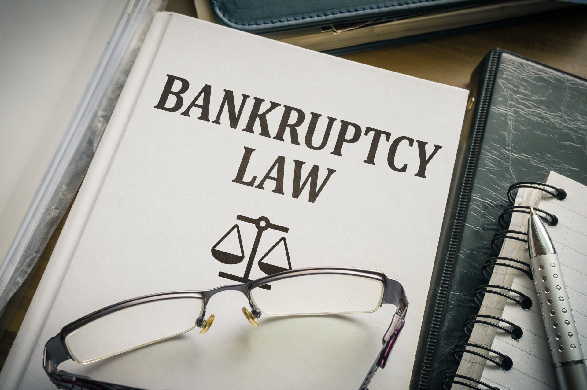 Bankruptcy law book with eyeglasses and justice scales on a desk