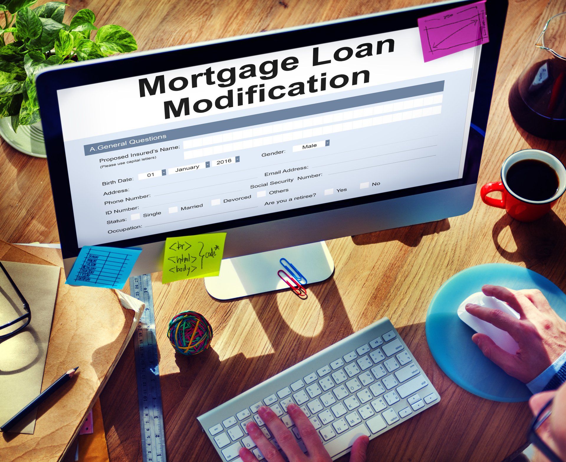 Mortgage loan modification form on a desktop computer, with sticky notes, keyboard, and coffee on a desk.