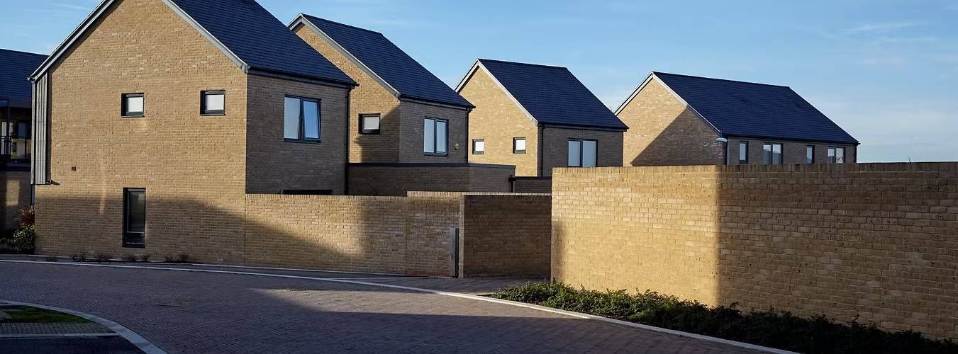 Row of modern brick houses with dark roofs under a clear blue sky
