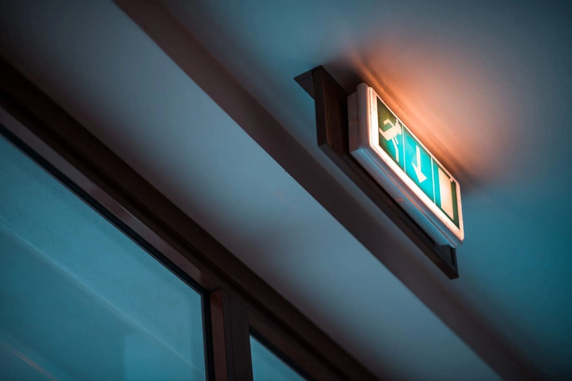 Illuminated fire exit sign mounted on a ceiling