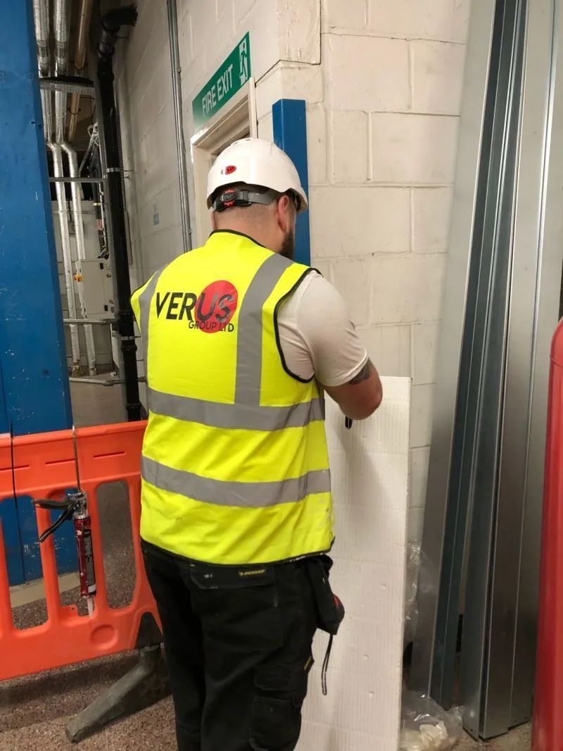 Verus Group technician fitting fire-rated board near a fire exit