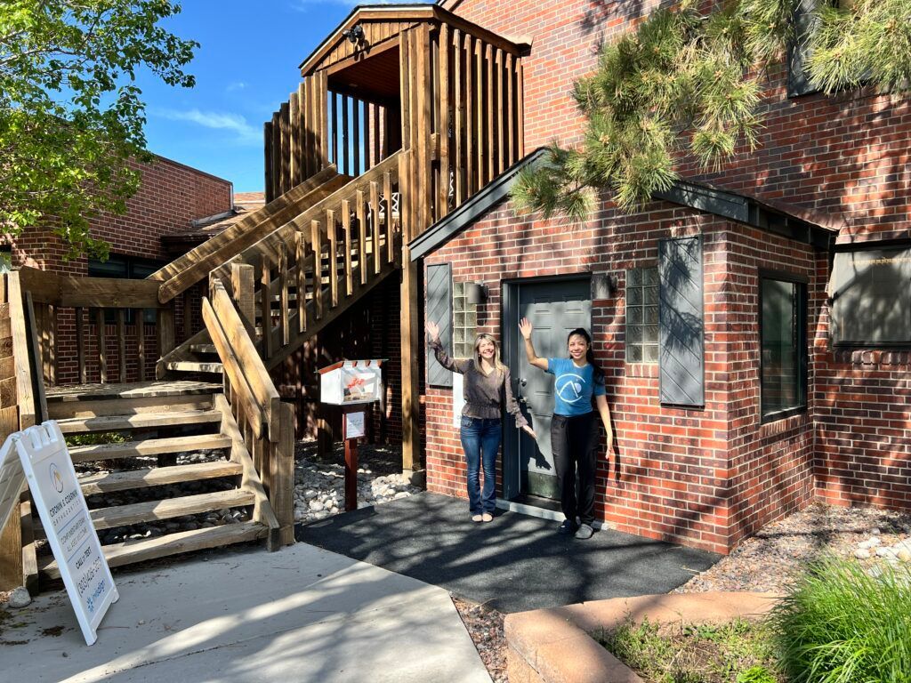Brick building entrance with exterior wooden stairs and two people standing by the door