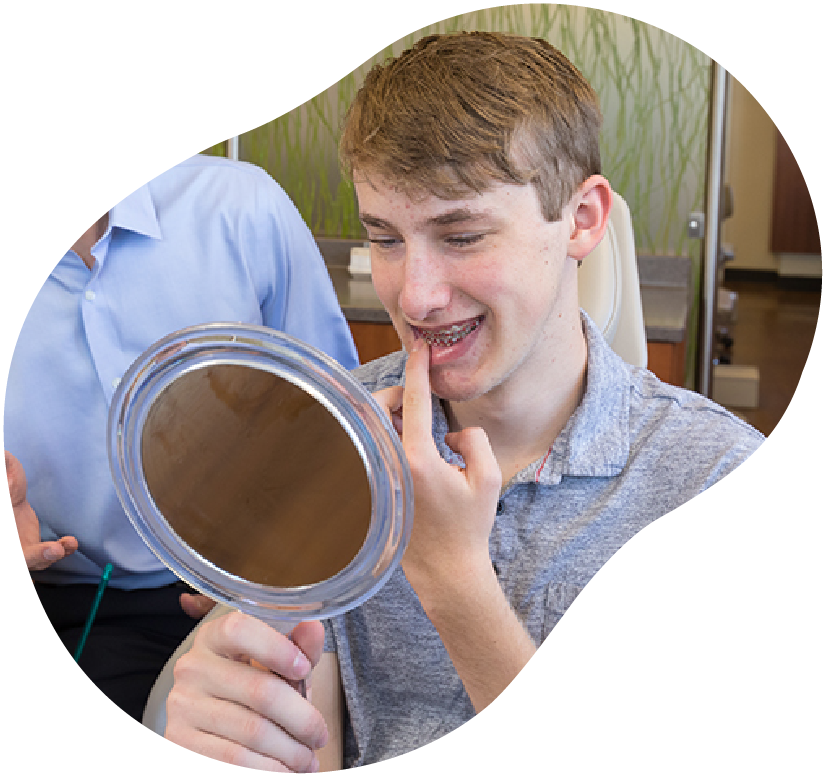 Person inspecting teeth with a handheld mirror in a dental office