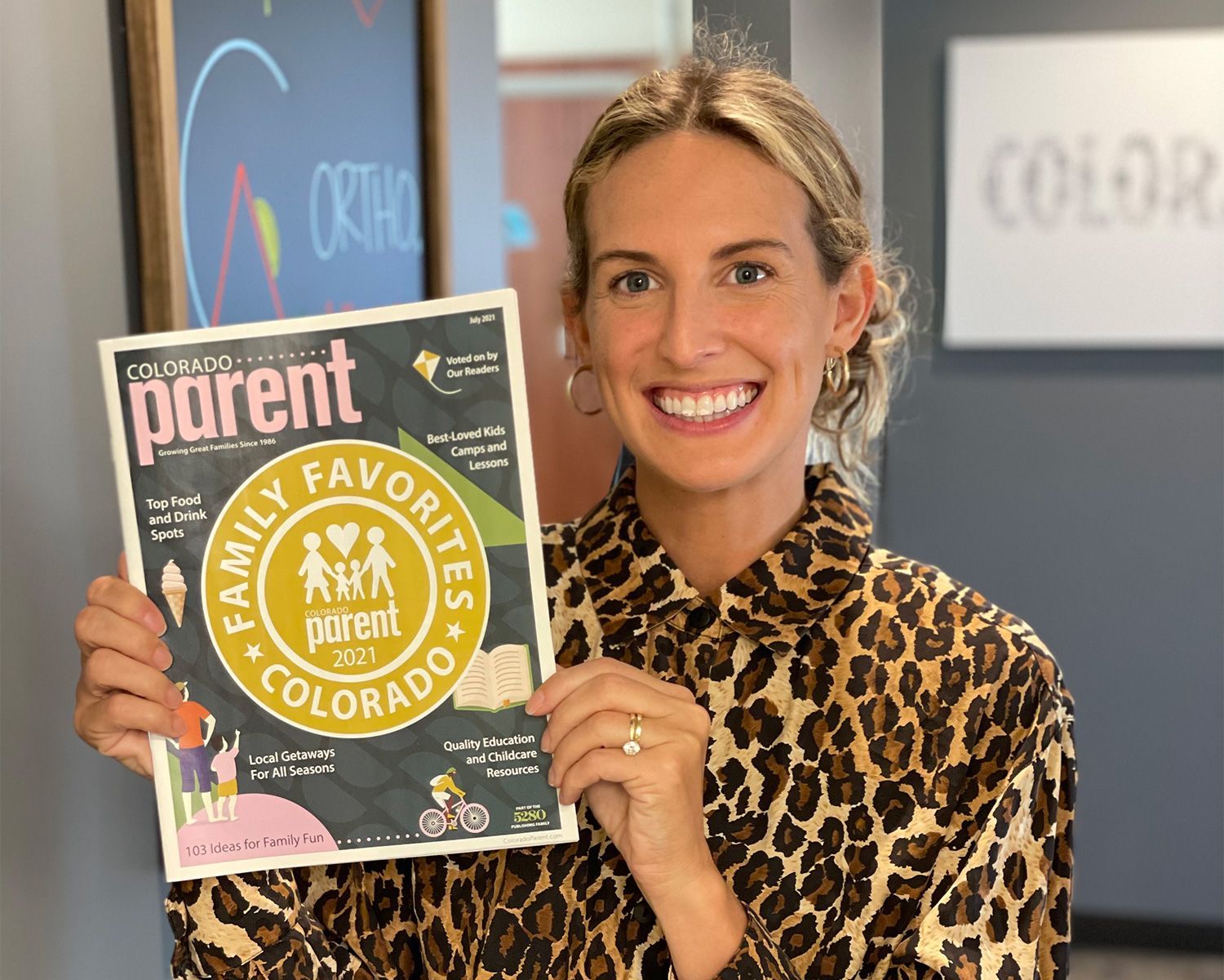 Woman smiling and holding a Parent Family Favorite award plaque in an office setting