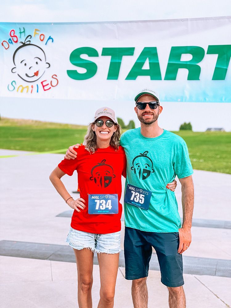 Two runners in red and teal shirts pose at the START line of a race.