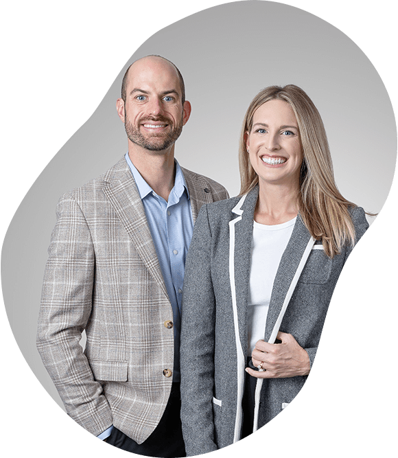 Two business professionals posing against a light gray background, smiling
