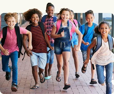 Smiling children with backpacks walking together on a school campus walkway